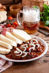 Traditional czech goulash with dumplings (knedliky) and beer on table