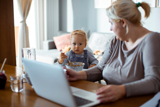Fototapeta Mother working from home with toddler