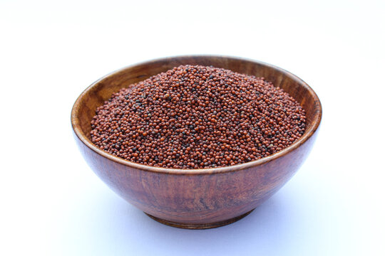 Organic Finger millet or Eleusine coracana in a wooden bowl on white background side view 