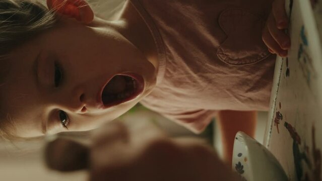 Mother's hands holding spoon feeding her little infant baby girl child. Home family breakfast.