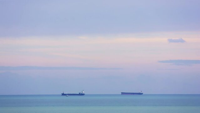 Sunset view at Mersin, Turkey with container ships anchored off coast. Container ship silhouettes against Mediterranean sunset. Container ship awaiting port entry near Turkish coastline