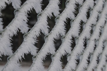 Zimowe rzeźby wiatru na siatce ogrodzeniowej. - obrazy, fototapety, plakaty