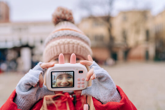 A girl captures herself on a toy camera, highlighting her joy and the essence of youthful curiosity