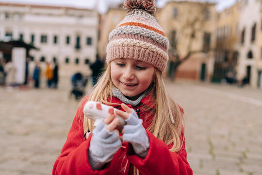 Intent and focused, a young girl with a camera takes a picture, immersed in the cultural backdrop of a Venetian square