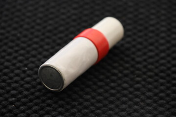 A small white and red spray tube with nitroglycerin on a black cloth. Life saving aid in the event of a heart attack or other acute heart problems.