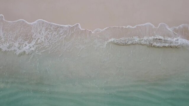 close up hovering over waves as the move onto soft beach at Turks and Caicos islands' Grace Bay 