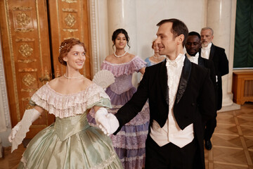 Portrait of classic renaissance couples following in line enjoying dance ball in palace