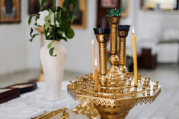 Burning candles in a gilded candlestick near the altar. Religious Christian accessories in the...