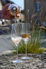 Pouring of premier cru sparkling rose wine with bubbles champagne with view on old houses of...