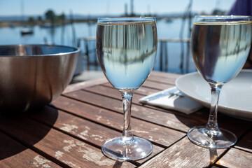 Drinking of white wine at farm cafe in oyster-farming village, with view on boats and water of Arcachon bay, Cap Ferret peninsula, Bordeaux, France - obrazy, fototapety, plakaty