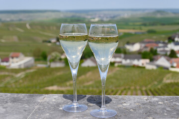 Tasting of grand cru sparkling white wine with bubbles champagne with view on houses and vineyards grand cru wine producer small village Cramant, Champagne, France