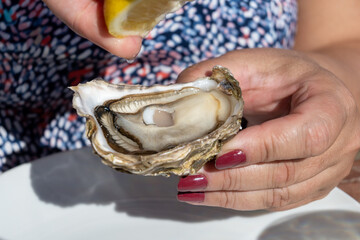 Eating of fresh live oysters at farm cafe in oyster-farming village, Arcachon bay, Cap Ferret...