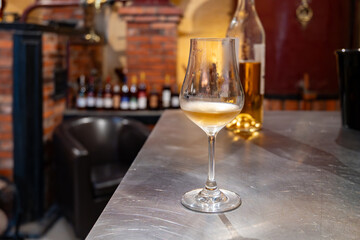Tasting of cognac spirit aged in old French oak barrels in cellar in distillery in Cognac white...