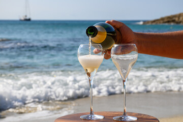 Summer time in Provence, two glasses of cold champagne cremant sparkling wine on sandy beach near...