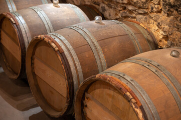 Wine cellar with wooden barrels in old wine domain on Sauternes vineyards in Barsac village...