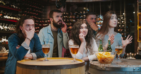 Caucasian male and female friends spending evening in bar when watching sport game. Men and women...