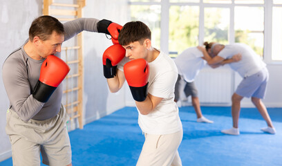Man and guy in boxing gloves punch deliver blow each other during training sparring session....