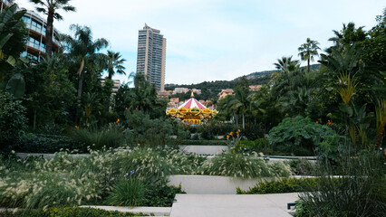 Scenic December view in Monaco, Carousel surrounded by lush greenery, set against the backdrop of the Monte Carlo Casino.