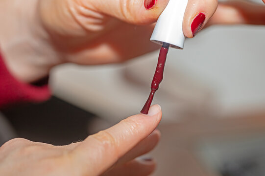 A woman who wears red nail polish on her fingernails.