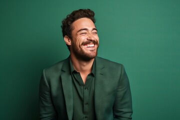 Portrait of a handsome young man laughing on a green background.