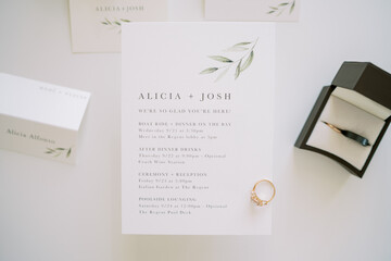 Engagement ring lies on a wedding invitation next to a box and name cards