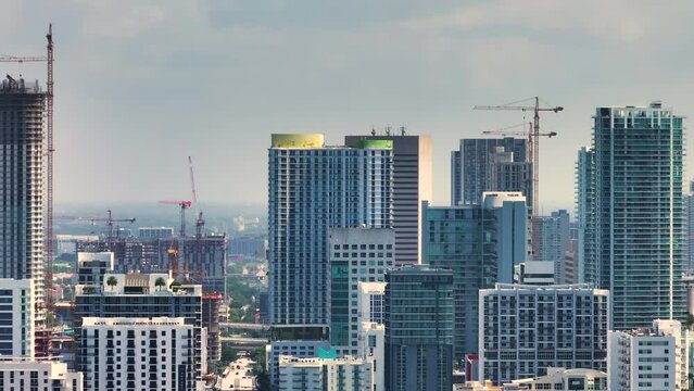 Real estate development in Miami urban area. Tower lifting cranes at high residential apartment building construction site