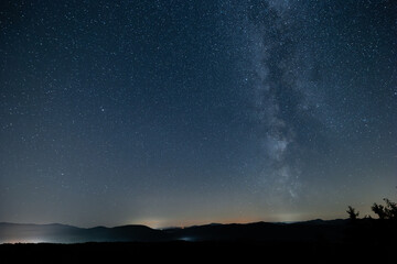 View of milky way from central europe or northern hemisphere. Sun has just set, visible silhouette of the hills. - obrazy, fototapety, plakaty