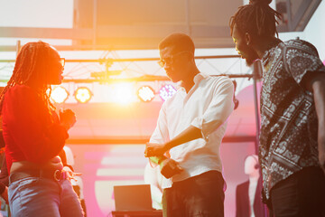 Young couple socializing and dancing in nightclub illuminated with vibrant stage spotlights. African american people clubbing and showing improvised moves on dancefloor at discotheque