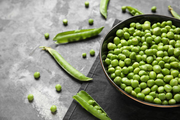 Bowl with fresh green peas on grey background