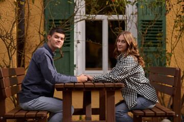 Teen Sweethearts: Holding Hands at an Outdoor Café in a European Town. Happy smiling young dating couple having coffee together and enjoying life sitting at table holding hands in street cafe on