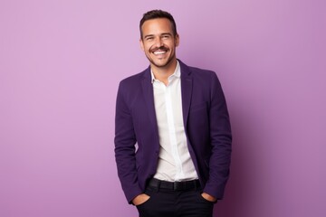 Portrait of a happy young man smiling and looking at camera against purple background