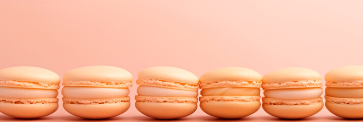 A row of macarons sitting on top of each other. Monochrome peach fuzz background.