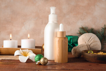 Cosmetic products, spa accessories and Christmas decor on wooden table against color wall