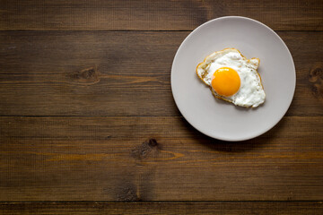 One fried egg on plate, top view. Breakfast background