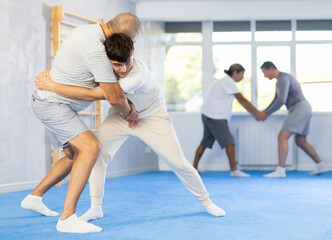 Obraz premium Two men of different ages in judo sparring - older man throws young guy to the mat