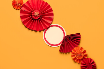 Blank card with paper fans on orange background. New Year celebration