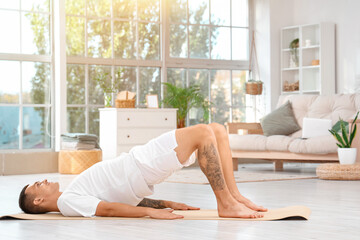 Young man doing yoga on mat at home