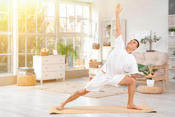 Young man doing yoga on mat at home