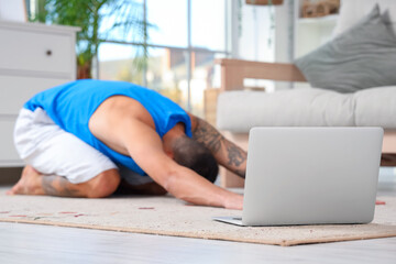 Laptop of young man doing yoga on carpet at home, closeup - obrazy, fototapety, plakaty