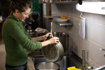 Mid Adult Woman Washing Commercialt Kitchen