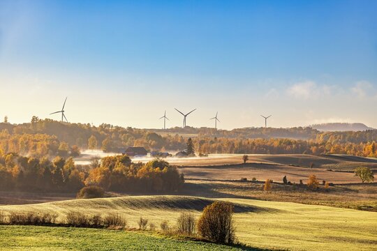 Landscape view with autumn fog by the fields and farms and wind turbines on the horizon, Sweden, Europe