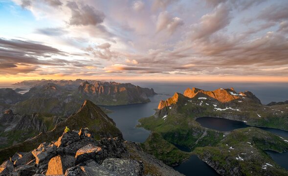 View over mountain peaks and sea, dramatic sunset, mountaineers at Hermannsdalstinden, with lakes Litlforsvatnet and Tennesvatnet and fjord Forsfjorden, Moskenesoey, Lofoten, Nordland, Norway, Europe
