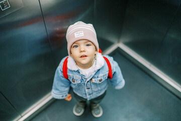 Little girl stands in an elevator with her head up