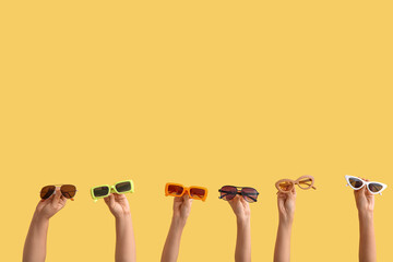 Female hands with different sunglasses on color background