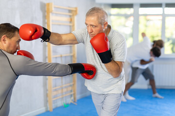 Male co-participant and senior man sparring partners during training battle fight using technique...