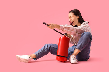 Scared young woman with fire extinguisher on pink background