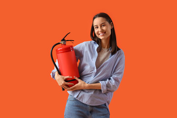 Young woman with fire extinguisher on orange background - obrazy, fototapety, plakaty