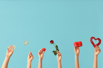 Female hands with decorative hearts, red rose and gift box on blue background. Valentine's Day...