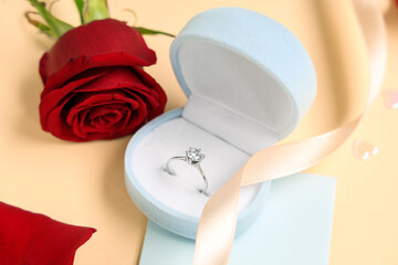 Beautiful composition with engagement ring and rose flower on yellow background. Valentine's day...
