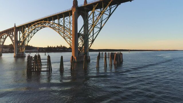 Aerial Drone Video- Yaquina Bay Bridge Sunrise- Newport Oregon- Full backward reveal of bridge and bay - boat crossing l to r V03